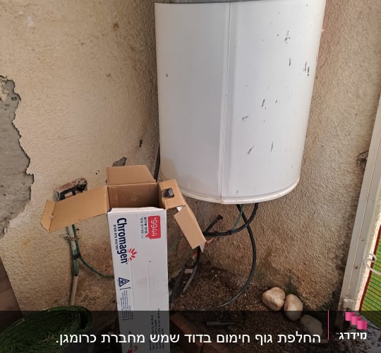 דוד שמש מותקן על קיר עם צינורות וחלקי קרטון